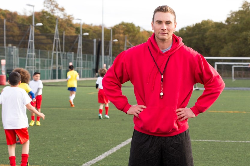 coach posing with a red hooded sweatshirt